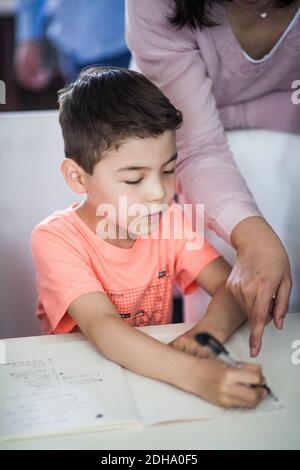 Midsection of mother assisting son in homework at home Stock Photo