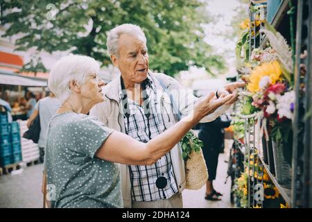 Retired couple discussing while shopping for flowers at market in city Stock Photo