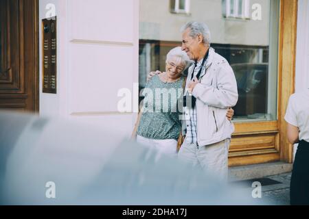 Happy elderly couple with arm around walking on sidewalk in city Stock Photo