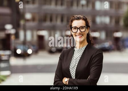 Portrait of smiling businesswoman with arms crossed standing outdoors Stock Photo