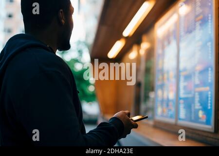 Side view of young man looking at menu while holding smart phone Stock Photo