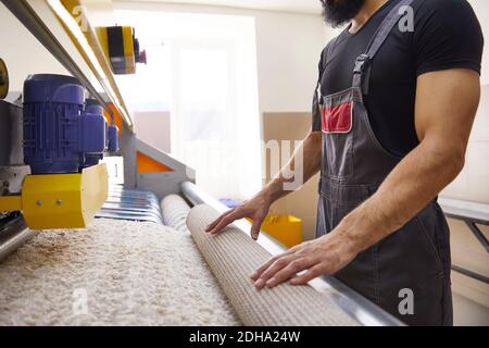 Man operating carpet automatic washing machine in professional laundry service Stock Photo