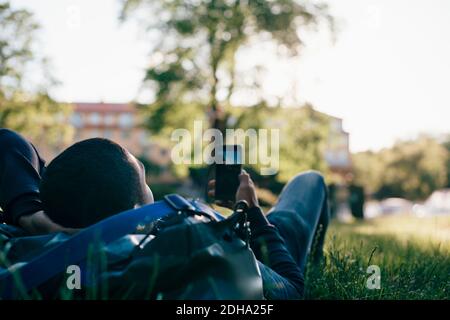 Young man using mobile phone while lying on grass Stock Photo