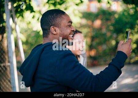 Side view of cheerful man photographing from smart phone Stock Photo