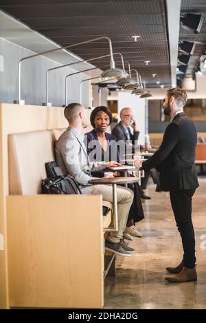 Young businessman talking with colleagues while drinking coffee in office Stock Photo