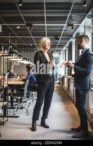 Senior businesswoman discussing with male coworker while standing in office Stock Photo