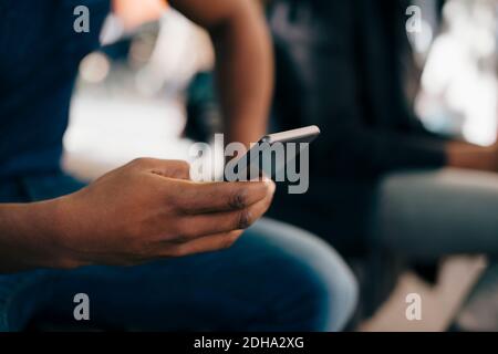 Cropped image of young man using smart phone in city Stock Photo