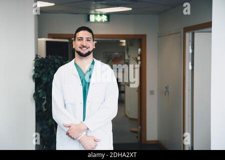Portrait of confident young male doctor standing in hospital corridor Stock Photo