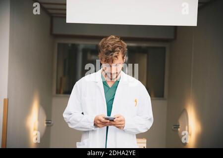 Young male doctor using mobile phone at hospital Stock Photo