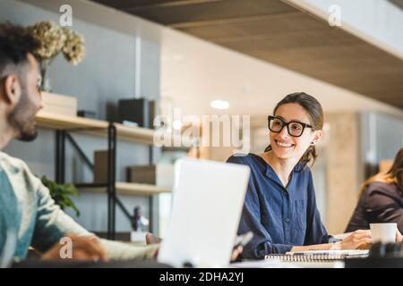 Smiling businesswoman looking at coworker while working in creative office Stock Photo