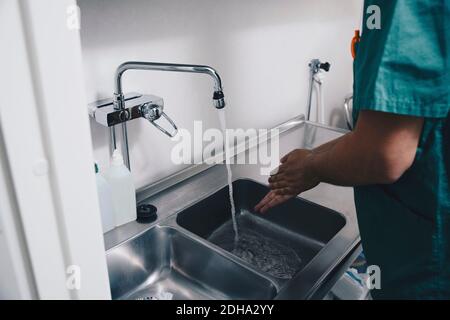 Cropped image of male nurse washing hands in sink at hospital Stock Photo