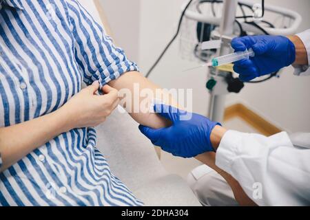 Cropped hands of doctor injecting female patient on arm in hospital Stock Photo
