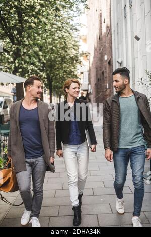 Full length of business colleagues walking on sidewalk against building in city Stock Photo
