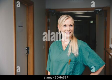 Smiling mid adult female nurse standing in hospital corridor Stock Photo