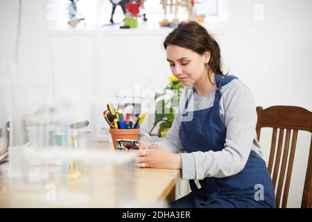 Young female engineer using smart phone at table in workshop Stock Photo