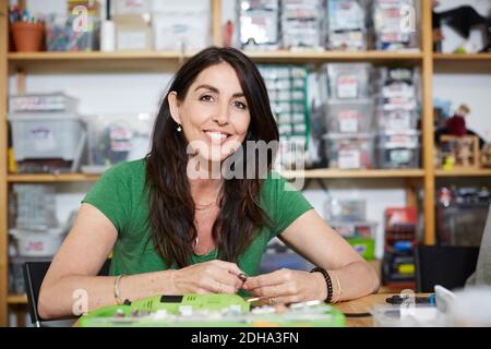 Portrait of smiling mature female engineer working at table in workshop Stock Photo