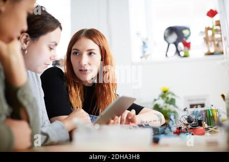 Multi-ethnic female technicians using digital tablet at table in workshop Stock Photo