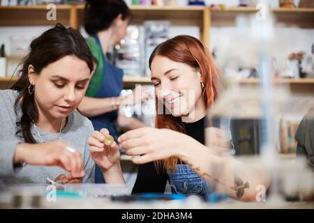 Smiling young female engineer holding electrical component by colleague at workshop Stock Photo