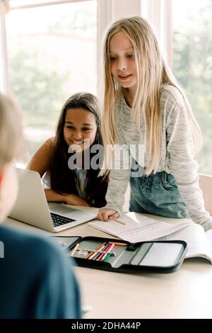 Female student looking while standing by friend in classroom Stock Photo