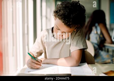 Male student writing while sitting in classroom Stock Photo