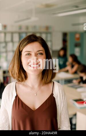 Portrait of smiling female tutor standing in classroom Stock Photo