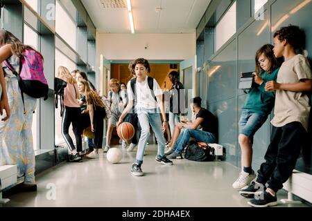 Male student playing with basketball during lunch break in school corridor Stock Photo