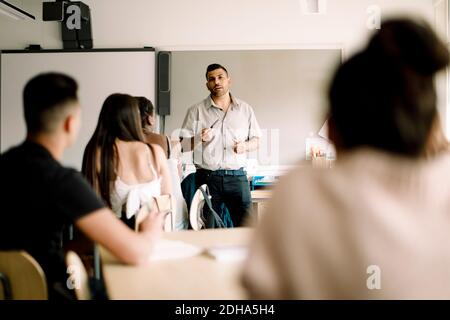 Professor teaching while teenage students sitting in classroom Stock Photo