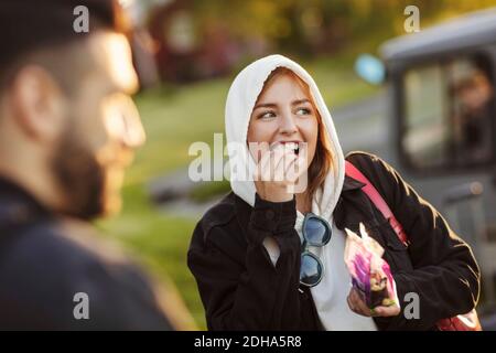 Cheerful young woman eating by man while looking away Stock Photo