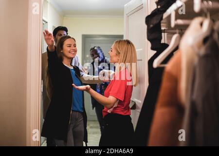 Smiling female friends hugging while standing in doorway with men Stock Photo