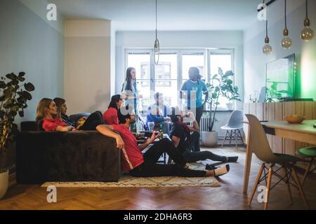 Male and female fans watching soccer match in living room Stock Photo