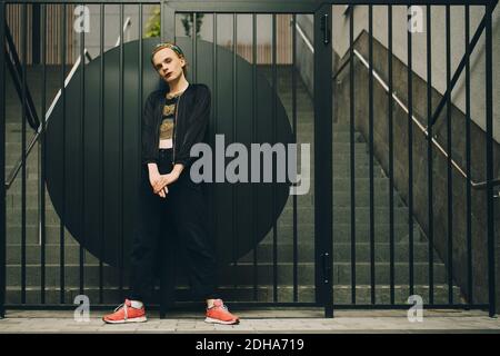 Portrait of confident young man standing against railing Stock Photo
