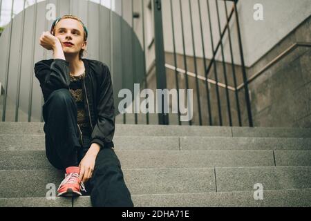 Contemplating young man looking away while sitting on steps Stock Photo