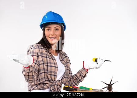 Handywoman electrician with screwdrivers and hardhat posing on white background. Stock Photo