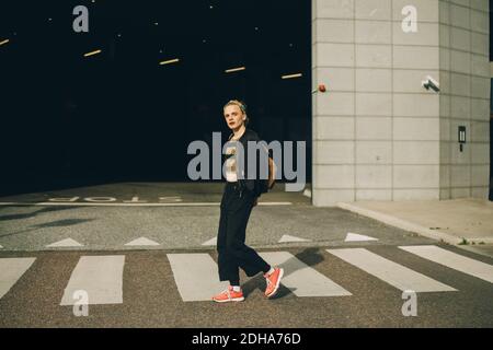 Portrait of man with hands behind back crossing road Stock Photo