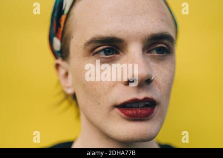 Confident young man looking away while standing against yellow background Stock Photo