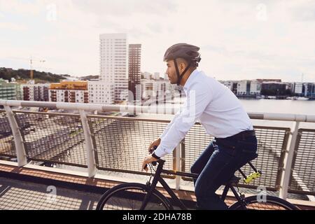 Side view of man cycling on footbridge against sky Stock Photo