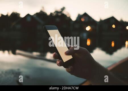 Cropped image of man text messaging through smart phone at lake Stock Photo