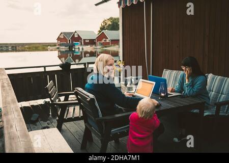 Woman talking to daughter while friend using laptop at table Stock Photo