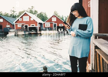 Woman using smart phone while standing by lake Stock Photo