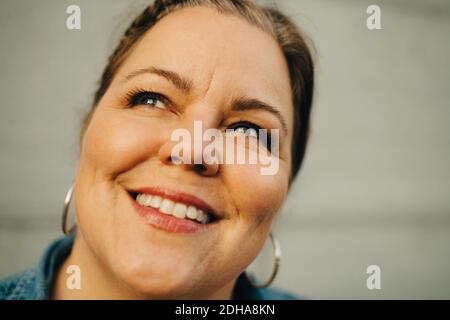 Close-up of smiling mature woman against wall Stock Photo