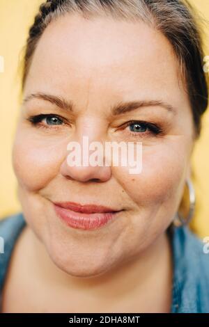 Close-up portrait of smiling woman against yellow background Stock Photo