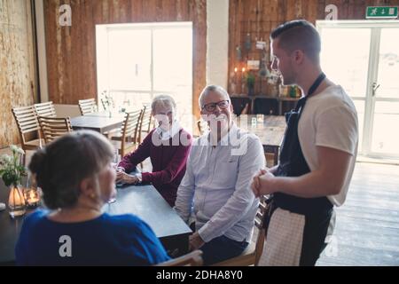 Young waiter taking order from senior people in restaurant Stock Photo