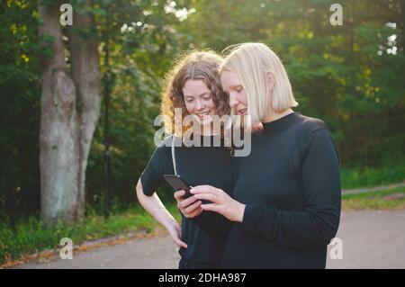 Female students using mobile phone outside university Stock Photo