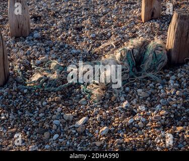 Discarded ropes and parts of fishing nets seen on the pebble and shingle beach. Stock Photo