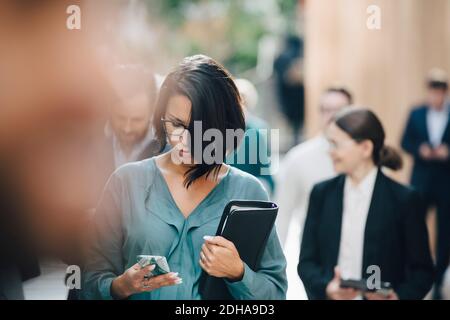 Female entrepreneur using smart phone outside office Stock Photo