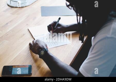 High angle view of businessman writing in diary at table in creative office Stock Photo