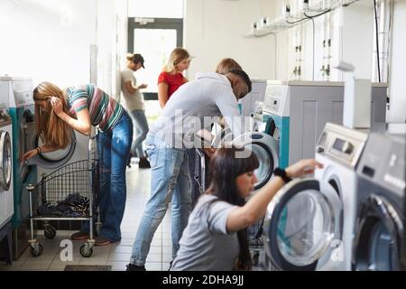 University students using washing machines at campus laundromat Stock Photo