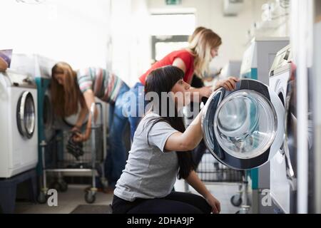 Female university students using washing machine at laundromat Stock Photo