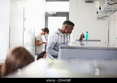 Young man using washing machine in campus laundromat Stock Photo