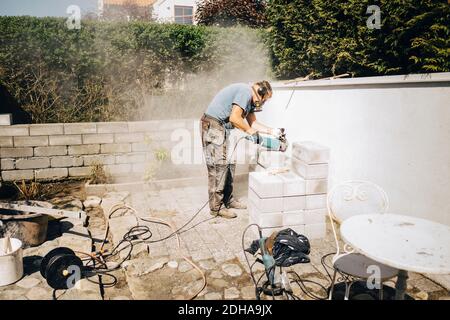 Full length of senior manual worker using grinder on wall Stock Photo